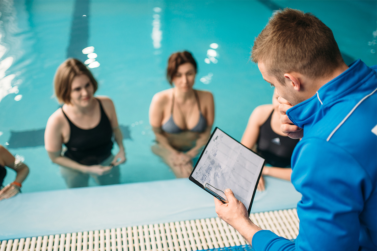 Kinésiologue effectuant un programme d'entrainement à des personnes dans une piscine.