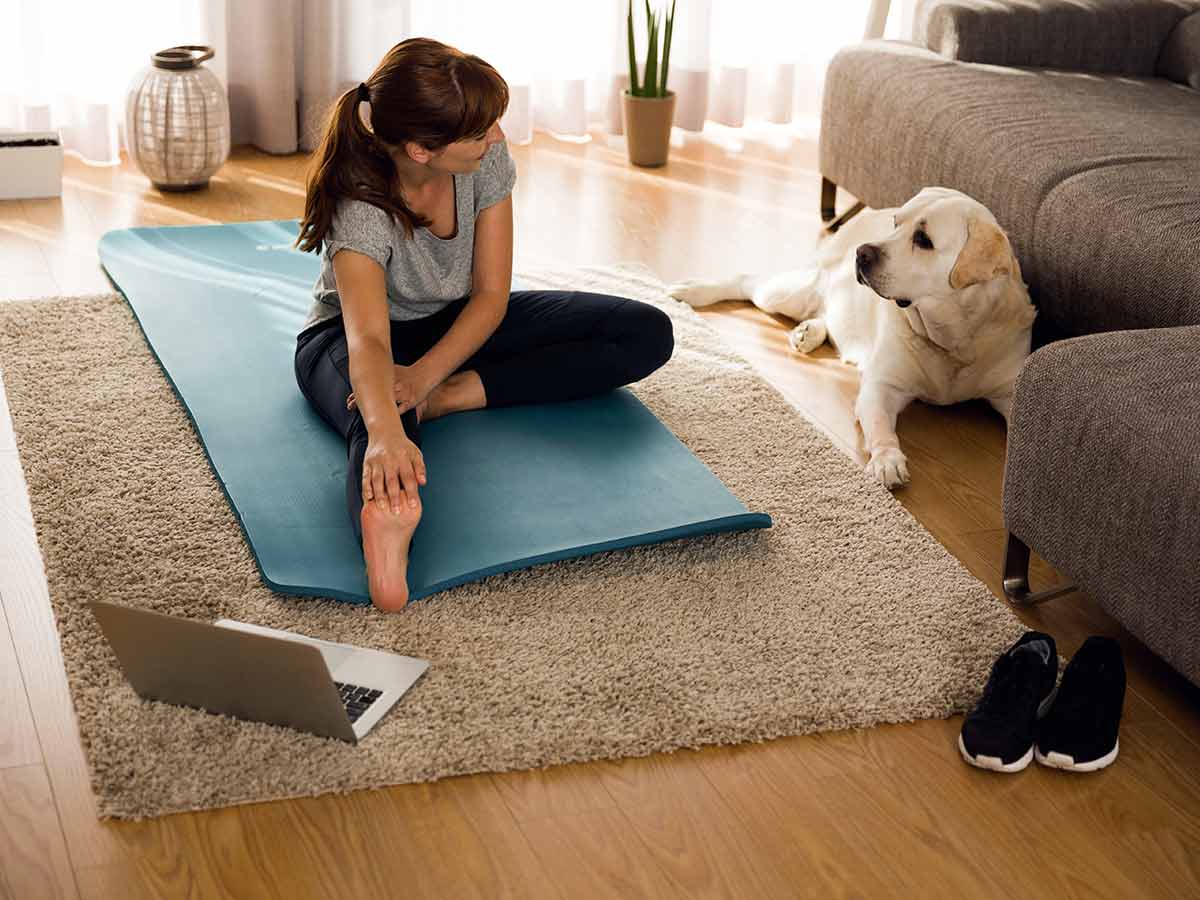 femme faisant de l'exercice à la maison avec son chien à côté